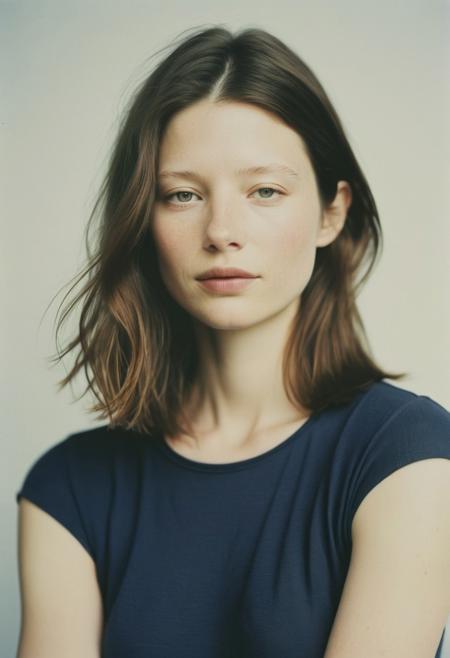 Model: (Catherine Keener:0.3), (Mia Goth:0.8).
Polaroid headshot for character casting:
- Standing against plain, light-colored background (off-white or pale gray)
- Soft, even natural lighting from large window or diffused studio lights
- Neutral facial expression, slight hint of intrigue in eyes
- Relaxed posture, shoulders slightly angled
- Simple, solid-colored clothing (muted tones, no patterns)
  - Options: plain white t-shirt, black turtleneck, or navy blue blouse
Two shot types:
1. Head-and-shoulders shot:
   - Framed from mid-chest up
   - Clear view of facial features and hair
   - Slight tilt of head for dimension
2. Full-body shot:
   - Entire figure visible, from head to feet
   - Natural standing pose, weight slightly on one leg
   - Arms relaxed at sides or one hand in pocket
Technical details:
- Polaroid-style frame visible
- Square format (3.5 x 4.25 inches)
- Slightly desaturated colors, characteristic of Polaroid film
- Subtle film grain and light vignetting
- Sharp focus on eyes, softening towards edges
- No visible makeup or hair styling, natural look
- Minimal shadows, emphasis on even lighting
- Authentic Polaroid texture and color shifts
Composition:
- Subject centered in frame
- Negative space around figure for potential cropping
- Eye level camera angle
Mood:
- Professional yet approachable
- Captures essence of character rather than glamour
