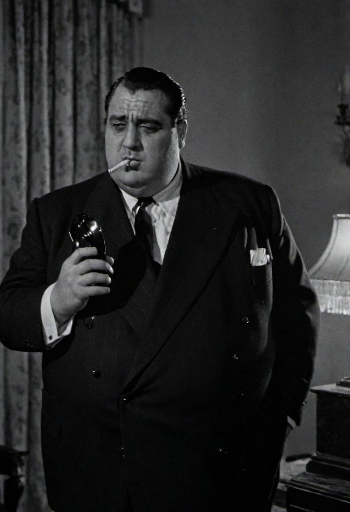 A man in a suit and tie smoking a cigarette.