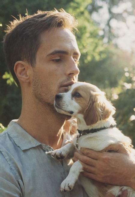 cinematic film still fashion photography portrait of 1man with dog as companion, grainy, headshot, sunlight , Fine Art & Beauty Photography – ,,light diffraction in frame, dreamy,hazy look.  Helios 44-2 lens mounted on a Praktica MTL 5B Helios 44M-4 lens, 58mm f/2,   in a garden.