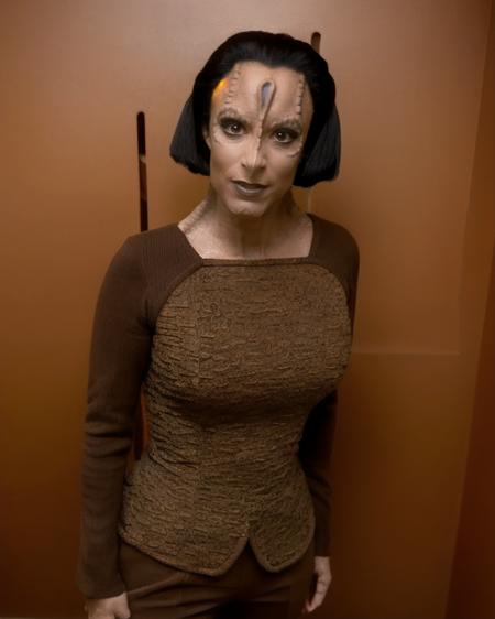 cardassian, female, iliana, grey skin, black swept back updo long hair, wearing greenish brown lipstick, wearing eyeliner, reptile scales on sides of neck, serious expression, wearing brown tunic and brown trousers, wide shot, front view, (raw photo:1.2), fujifilm x100v, standing in a copper colored room, 8k, nana visitor, <lora:cardassian_lora_v2:0.7>, <lora:locon_perfecteyes_v1_from_v1_64_32:0.3>