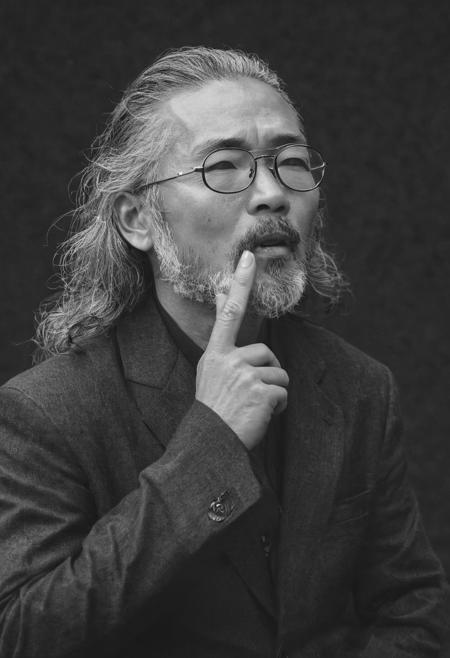 during interview cover photograph of 48 year-old japanese fashion designer (confident expression:1.2, body:1.1), talking with mouth open, hands down, outdoor studio setting, grey long hairstyle,long grey beard, silver glasses, smoking cigar, in the act of calm and mindfulness, high fashion clothing, with a focus on his face and upper body,soft strong natural lighting,high resolution,, high contrast, ray og light, light on the eyes, hard shadow, ENF, Cover