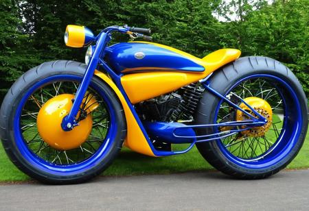 photo of a low-slung wide,futuristic muscle motorcycle TRIKE. STREAMLINED FULLY ENCASED BODY, YELLOW and ORAANGE AND BLUE, LARGE FAT TYRES