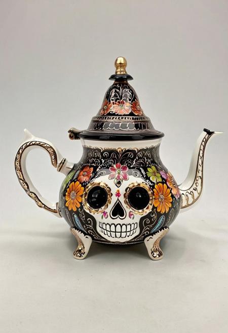 An ornate teapot designed in the shape of a sugar skull, richly decorated with traditional Día de los Muertos floral patterns and colorful motifs, intricate ceramic detailing with hand-painted roses, marigolds, and swirls, glossy porcelain texture, elegant curved spout and handle, resting on a lace-covered wooden table, soft ambient lighting, high detail, photorealistic style, 4k resolution, whimsical and cultural aesthetic
Atai