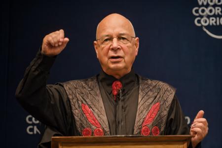 klaus schwab, standing behind a black podium, red background, <lora:klaus_schwab_v1_1:0.8>
