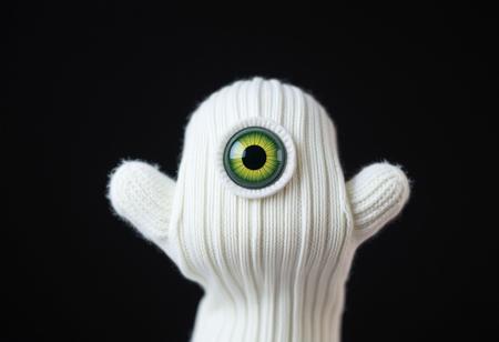 a white sock puppet with one central alien eye