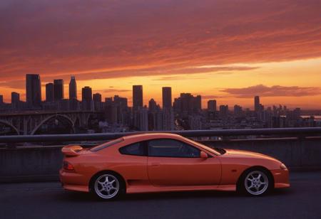 (1996 Hyundai Tiburon RD) motor vehicle, no humans, city, sky, outdoors, scenery, orange sky, road, building, cityscape, sunset, vehicle focus, skyscraper, sports car, shadow, gradient sky, red sky, evening, cloud, street, skyline, twilight, spoiler \(automobile\), orange background, dusk, red background, water, solo, bridge,