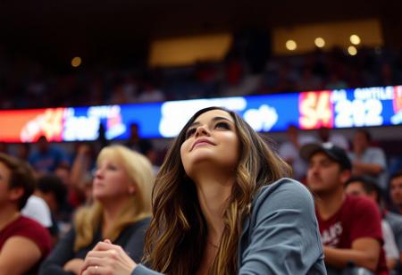 Authentic share, distant amateur quality phone photo in bad resolution of a stunningly beautiful fan at a basketball game The image is slightly grainy and out of focus, with visible noise, emphasizing its candid and impromptu nature captured in a spontaneous moment with imperfect lighting that adds to the overall charm of the snapshot.