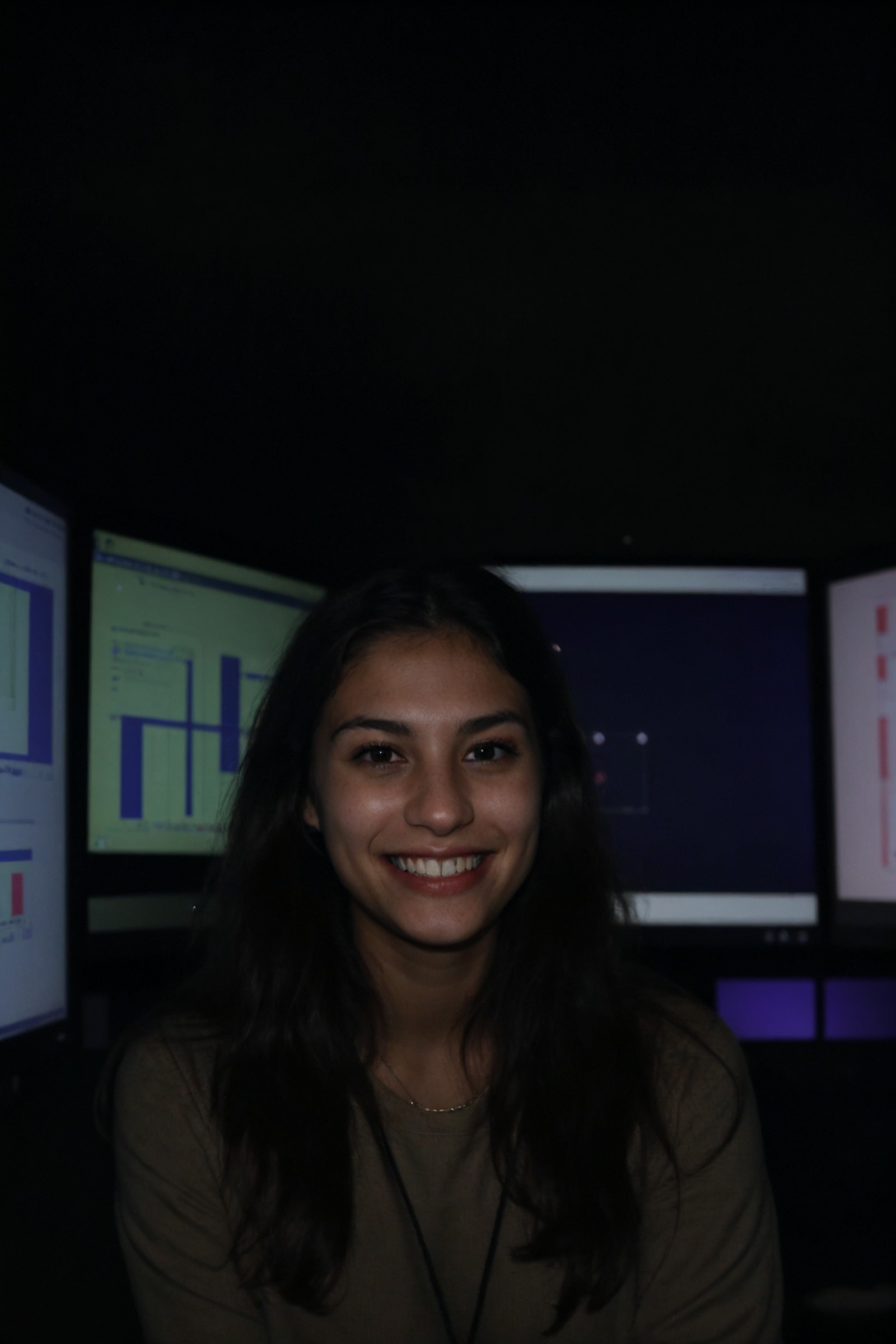 A female social worker having fun in a dark room surrounded by computer screens, poor quality photo, blurry, (smiling:0.5)...