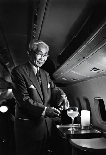 <lora:karsh_style_1-000008:1> monochrome karsh style, elderly asian man steward preparing a cocktail on an airplane, dimmed lights, full shot