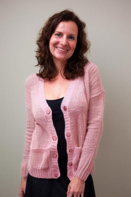 realistic photo of christa, a cute woman, pink knit cardigan, very huge natural bust, skirt, looking at the camera, standing, simple background, beautiful, (intricate details), ultra detailed, flash photography lighting
