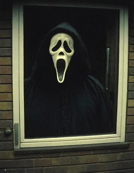 a cctv blurry image,high-angle,taken from a monitor,showing Ghostface from a doorbell view outside a house,vhs filter,(low resolution:1.3),grainy,eerie,horror,dark