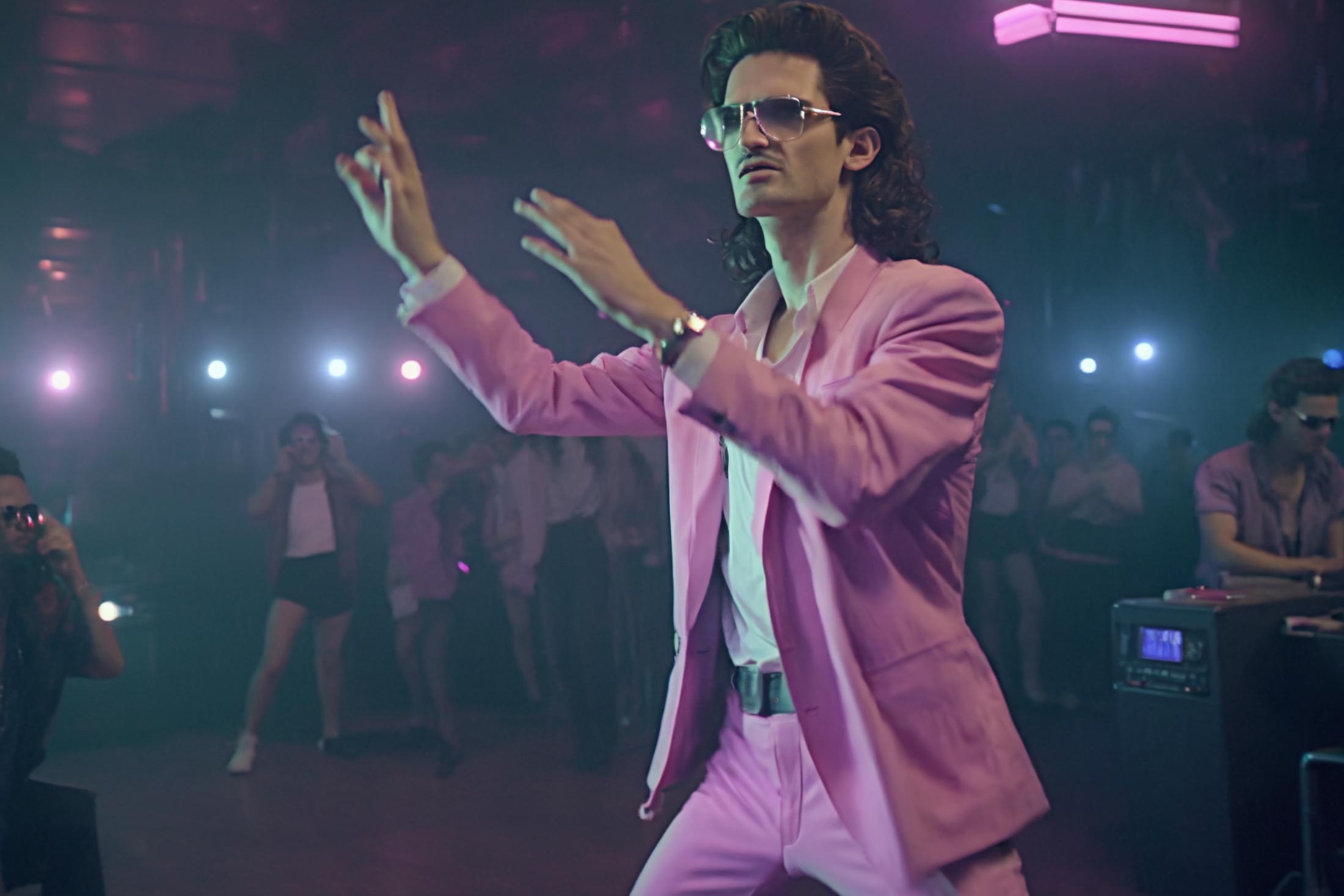 A man in a pink suit dancing and wearing sunglasses.