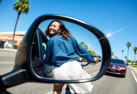 wide angle photograph of a car wing mirror with the reflection of A smiling woman dressed in a blue oversized shirt and a white pleated skirt, seen from behind and slightly turning her head back, riding a bicycle. The scene is set on a sunny day with clear blue skies, showcasing an urban street environment with cars and palm trees in the background. The image exhibits a light flare and is partially framed through a circular object, adding a unique visual effect to the composition. The overall mood is carefree and joyful, capturing a casual and stylish moment.