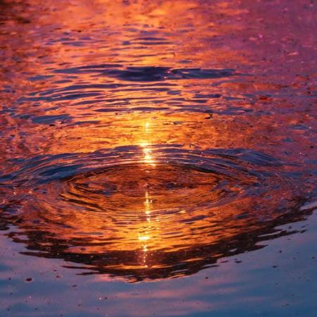 half angle, slightly from the side, warping of time and space, camera lens half way emerging from water, semi submerged rising through the water, with the most beautiful reflection of the colorful sunset, water droplets, refracting colorful light, color burst, explosion, fused, color bomb,